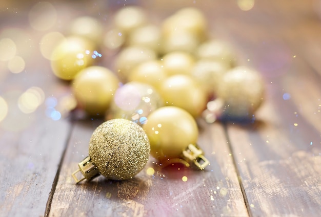 Christmas golden glittered balls on brown wooden table.