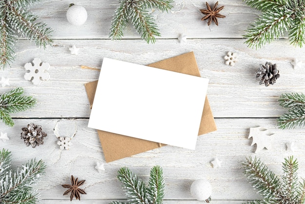 Christmas greeting card in frame made of fir tree holiday decorations on white wooden background Mock up