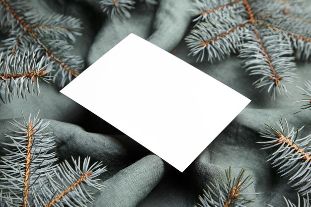 Christmas greeting card mockup with fir tree branches on green cloth background