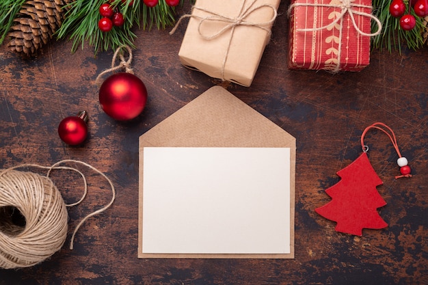 Christmas greeting card with fir tree branch, gifts, present box and envelope. Wooden background Top view