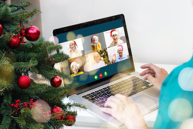 Christmas greetings online. a woman in a white sweater and red Santa hat uses a laptop to make video calls to friends, parents, and for online shopping.