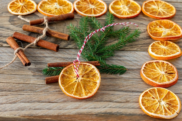 Christmas handmade natural decorations. Garland and fir tree toy made of dried slices of oranges on wooden table. Winter still life composition.