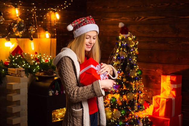 Christmas and happiness concept  a beautiful woman in santa hat helper with christmas gift in a red ...