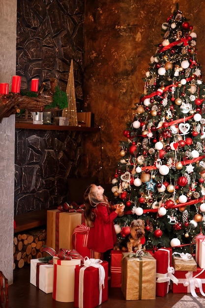 Christmas happiness little happy girl and dog near a huge Christmas tree with gifts family christmas