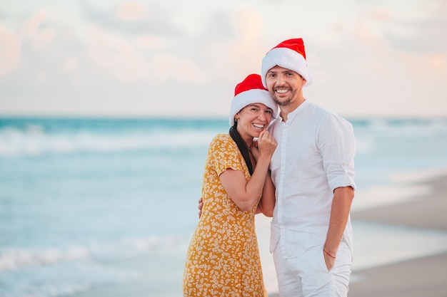 Christmas happy couple in Santa hats on beach vacation