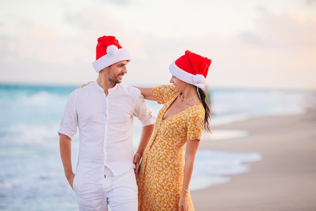 Christmas happy couple in Santa hats on beach vacation