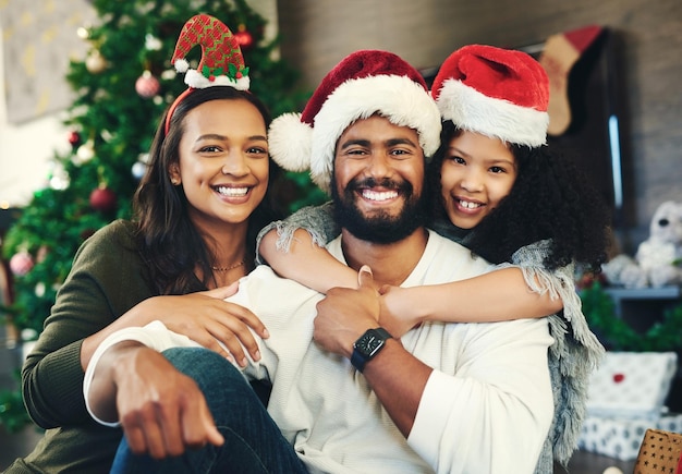 Christmas happy and portrait of family in living room for celebration affection and festive Holiday smile and bonding with girl hug parents at home for content gratitude and xmas vacation