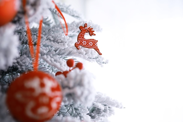 Christmas holiday background. Silver and color bauble hanging from a decorated on tree with bokeh and snow, copy space.