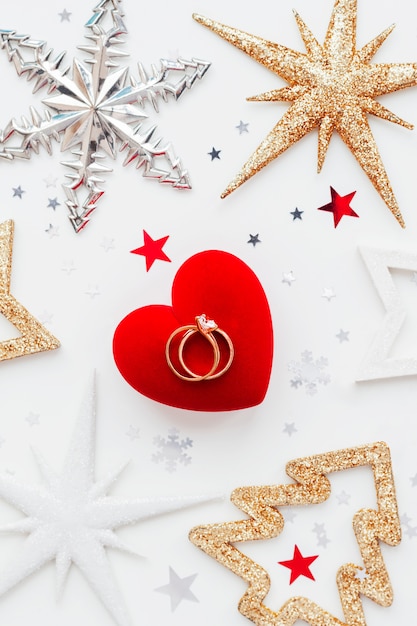 Christmas holiday background with decorations and wedding rings on gift heart box.