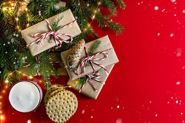 Christmas and holidays concept Flat lay with copy space red background treats for santa claus milk and cookies fir branches