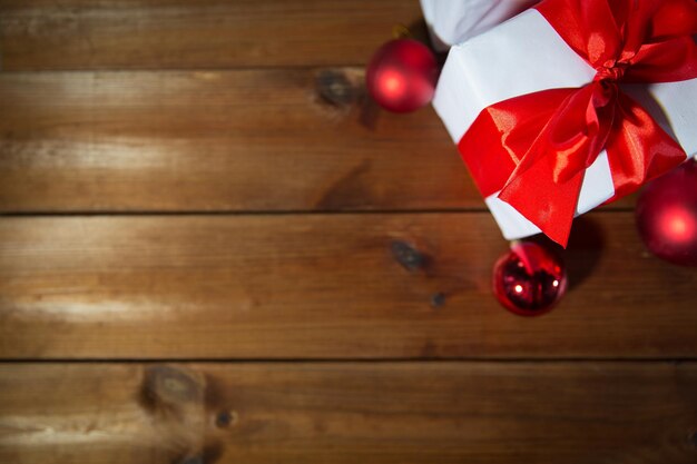 christmas, holidays, presents, new year and celebration concept - close up of gift boxes and red balls on wooden floor from top