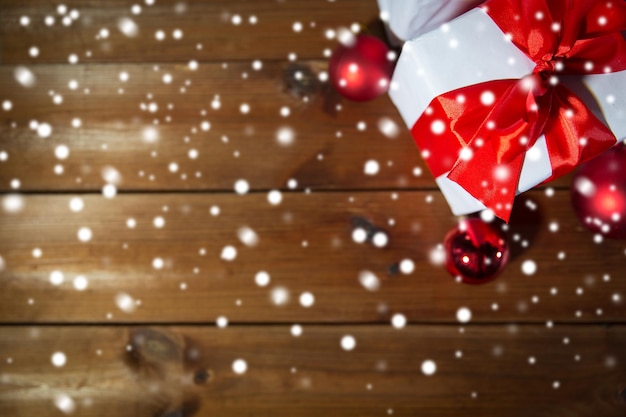 christmas, holidays, presents, new year and celebration concept - close up of gift boxes and red balls on wooden floor from top