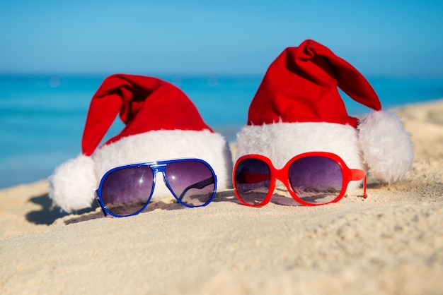 Christmas holidays and Romantic New Year at Sea. Santa hats and sunglasses on sandy beach