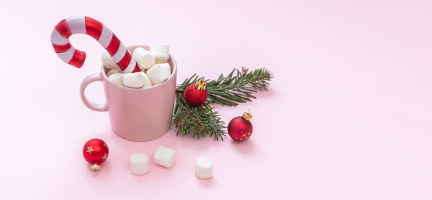 Christmas hot beverage chocolate mug marshmallows and Xmas decoration on pastel pink background