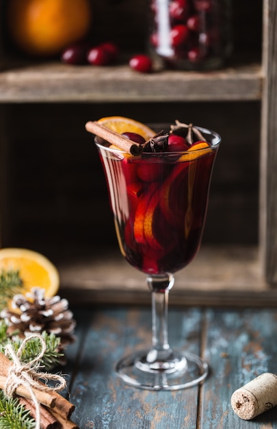 Christmas hot mulled wine in a glass with spices, citrus fruit and cranberry. Christmas atmosphere.