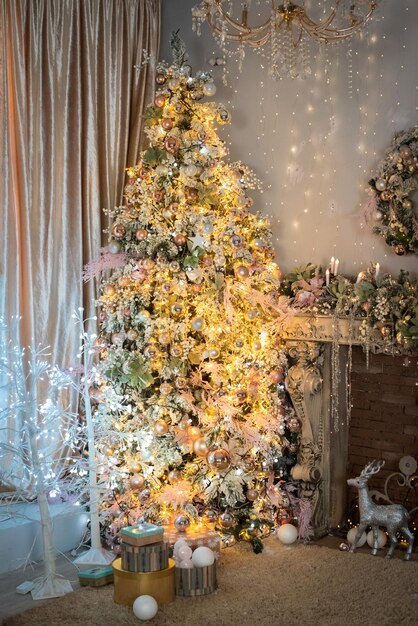 Christmas interior in pink and gold. Christmas tree and fireplace are decorated with shiny balls, lights. happy New Year.