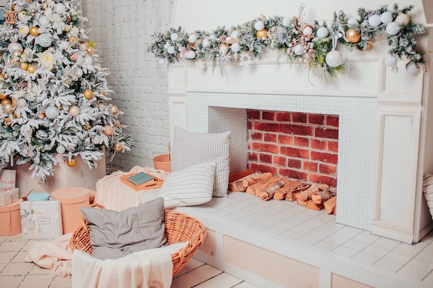 Christmas interior  in white colors. White wooden floor, christmas tree with ornaments, gifts, fireplace and basket. Christmas cosiness.