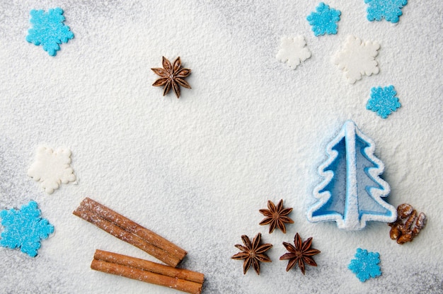 Christmas kitchen background made of flour, cinnamon sticks, anise,  cookie cutter and sugar sprinkles