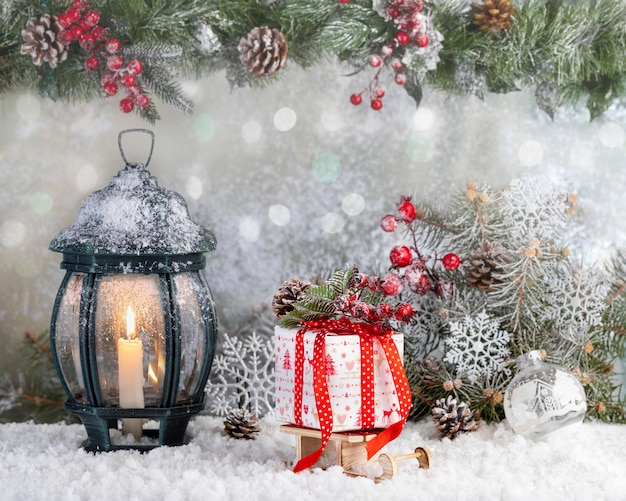 Christmas lantern and Gift box in the snow with fir branches