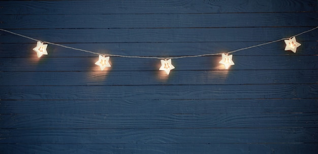 Christmas lights on blue wooden background