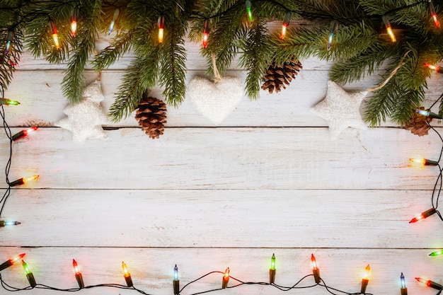 Christmas lights bulb and pine leaves decoration on white wood plank