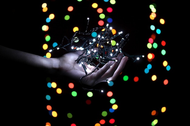 Christmas lights in hand on blur lights background