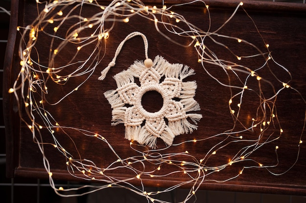 Christmas macrame toys snowflake on dark background Natural materials cotton thread wood beads and stick Eco decorations ornaments hand made decor Winter and New Year holidays