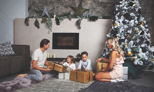 Christmas mood Family of mom dad daughter son open gifts Decorated Christmas tree and fireplace