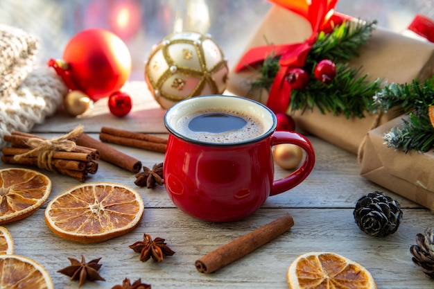 Christmas mood holiday atmosphere Red cup of coffee Christmas gift boxes Christmas tree golden ball cones star anise cinnamon on a wooden windowsill