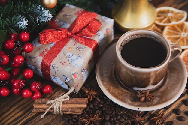 Christmas mood holiday atmosphere Red cup of coffee fir branches with cones Christmas gifts star anise on a wooden table background