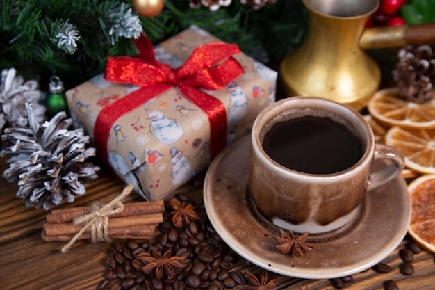 Christmas mood holiday atmosphere Red cup of coffee fir branches with cones Christmas gifts star anise on a wooden table background