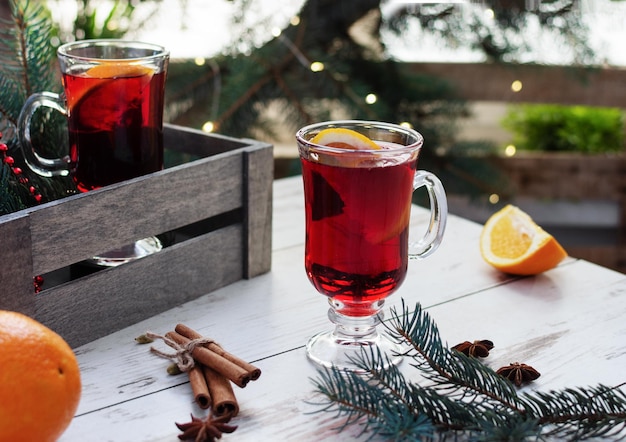 Christmas mulled red wine with spices and fruits over Christmas decorated background