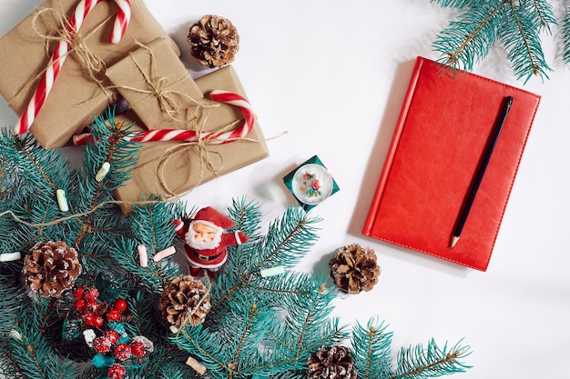 Christmas or new year background furtree branches gifts decoration red notebook with pen on a white ...