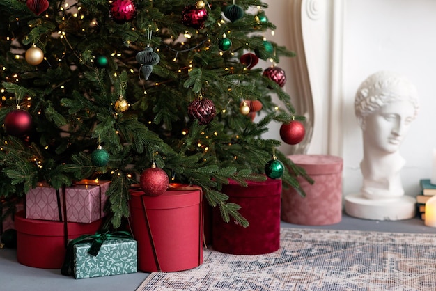 Christmas and New Year background - gift boxes and light garlands, bokeh, near a decorated Christmas tree. Soft selective focus.