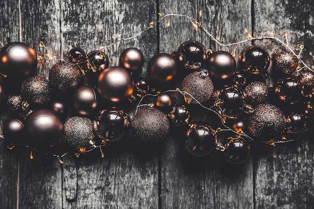 Christmas or New Year background. Vintage Christmas tree toy decoration balls and light garland over rustic wooden background, selective focus, copy space