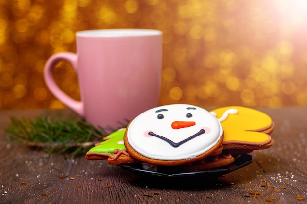 Christmas and New Year butter cookies in a plate and a mug near a fir tree branch on a blurred background