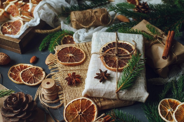 Christmas or New Year composition with handmade gifts dry oranges cinnamon fir tree on dark stone table