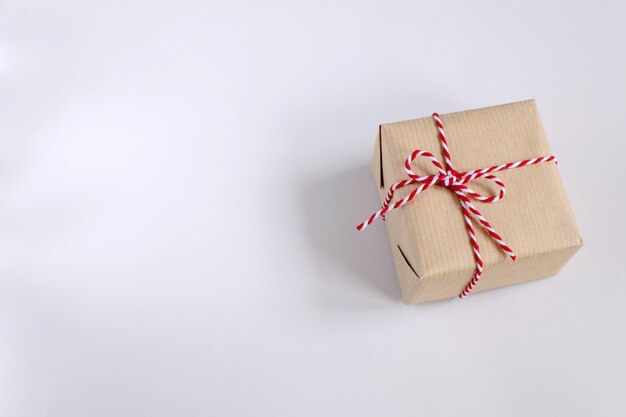 Christmas or New Year concept - present box in craft paper with twisted red and white cord.