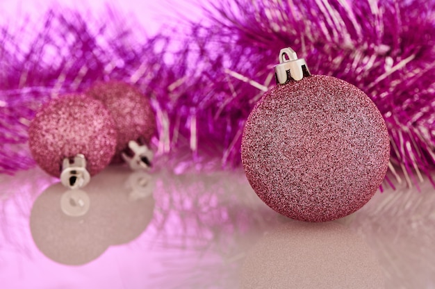 Christmas and New Year decorations. Pink Christmas tree balls and garland are on the table. Backlight with pink light.