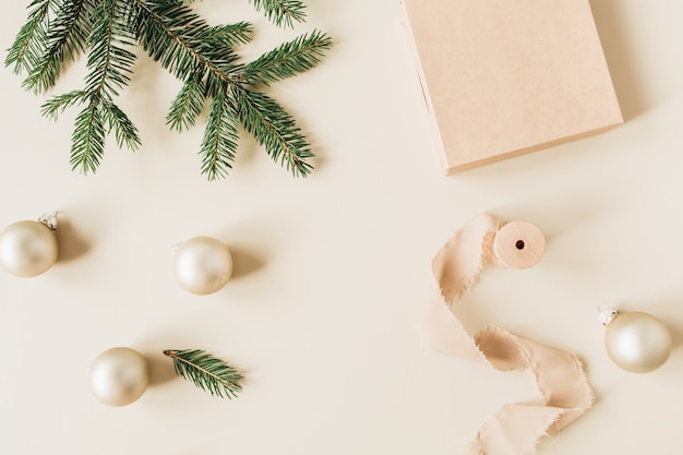 Christmas New Year holiday composition with fir needle branches, gift box, ribbons and gold Christmas baubles on beige