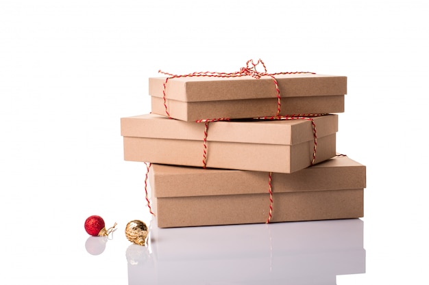 Christmas, New Year stacked gift boxes, parcel, present packed in eco-friendly paper tied with rope, with red and golden baubles with shadow isolated