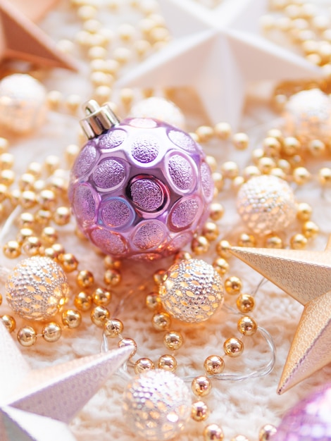 Christmas and New Year star decorations on white knitted . Metal light bulbs with delicate pattern, golden beads and violet balls.