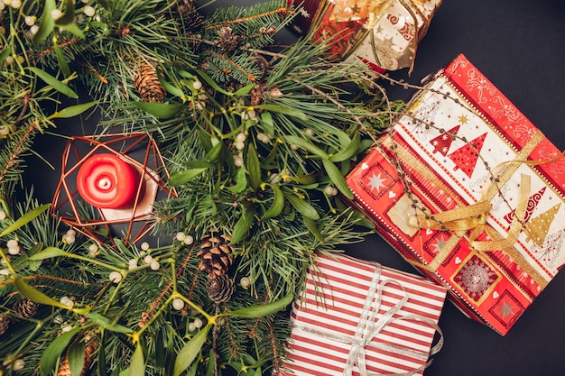 Christmas and New Year wreath made of fir, pine, mistletoe branches, cones with burning candle inside and gift boxes. Eco and natural home decoration