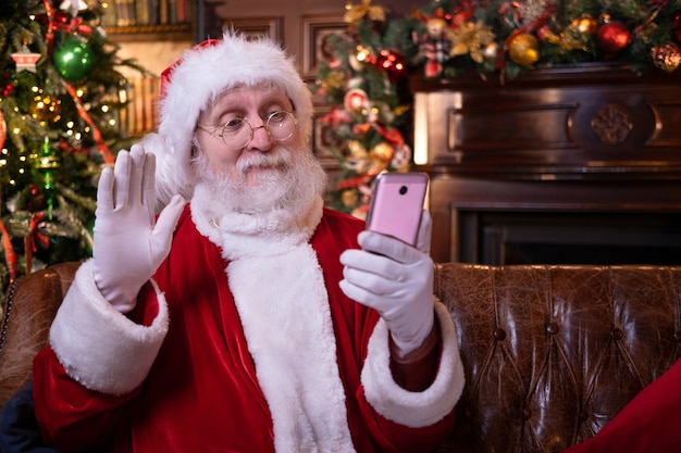 Christmas online congratulations from Santa. Santa Claus using mobile phone