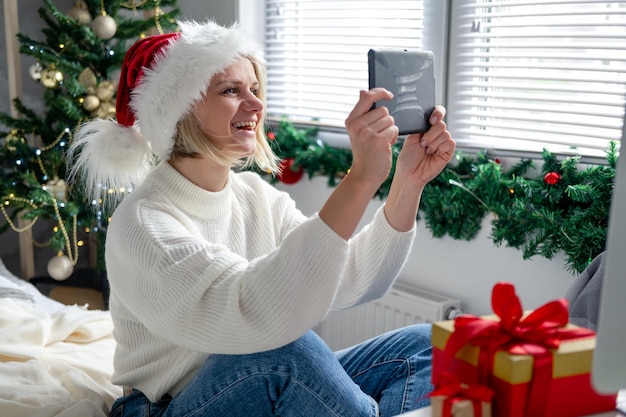 Christmas online congratulations Smiling woman using mobile tablet for video call friends and parents