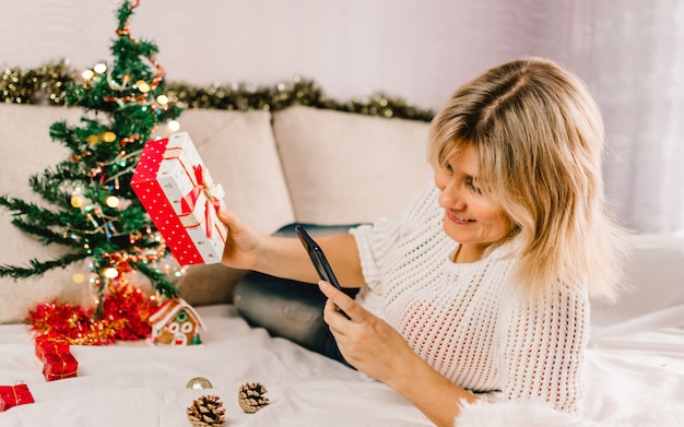 Christmas online shopping. Female buyer makes order on mobile phone.