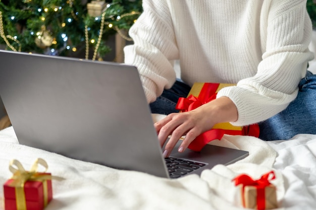 Christmas online shopping Girl makes order on laptop Woman buy presents prepare to xmas among gift boxes and packages Winter holidays sales