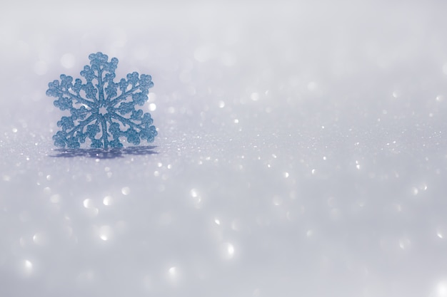 Christmas ornament on snow against blurred lights background