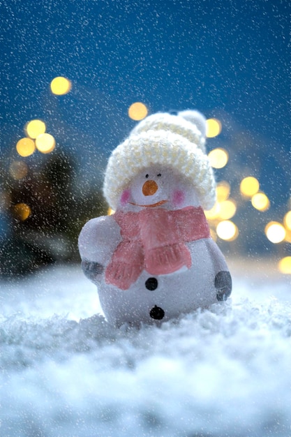 Christmas ornament snowman in the snow and bokeh lights Abstract winter seasonal background