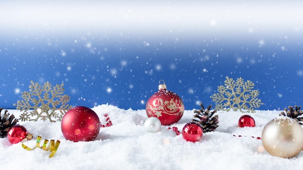 Christmas ornaments on snow over blue background with snowflakes